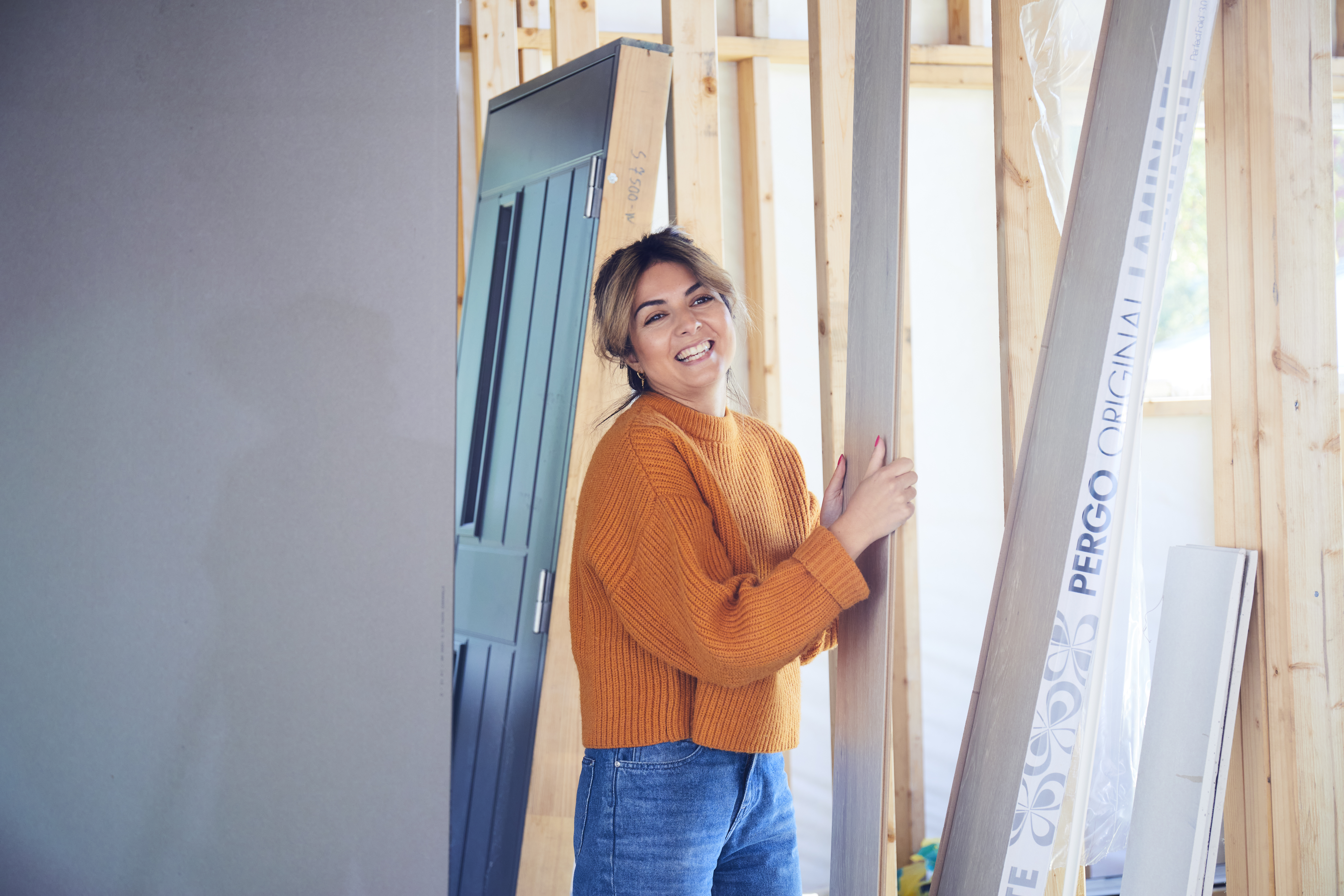 Dame med oransje genser holder pakke med Pergo gulv